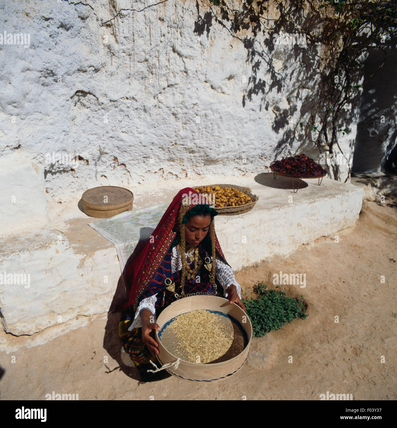 Berber girl in traditional clothes with a sieve, Matmata, Tunisia. Stock Photo