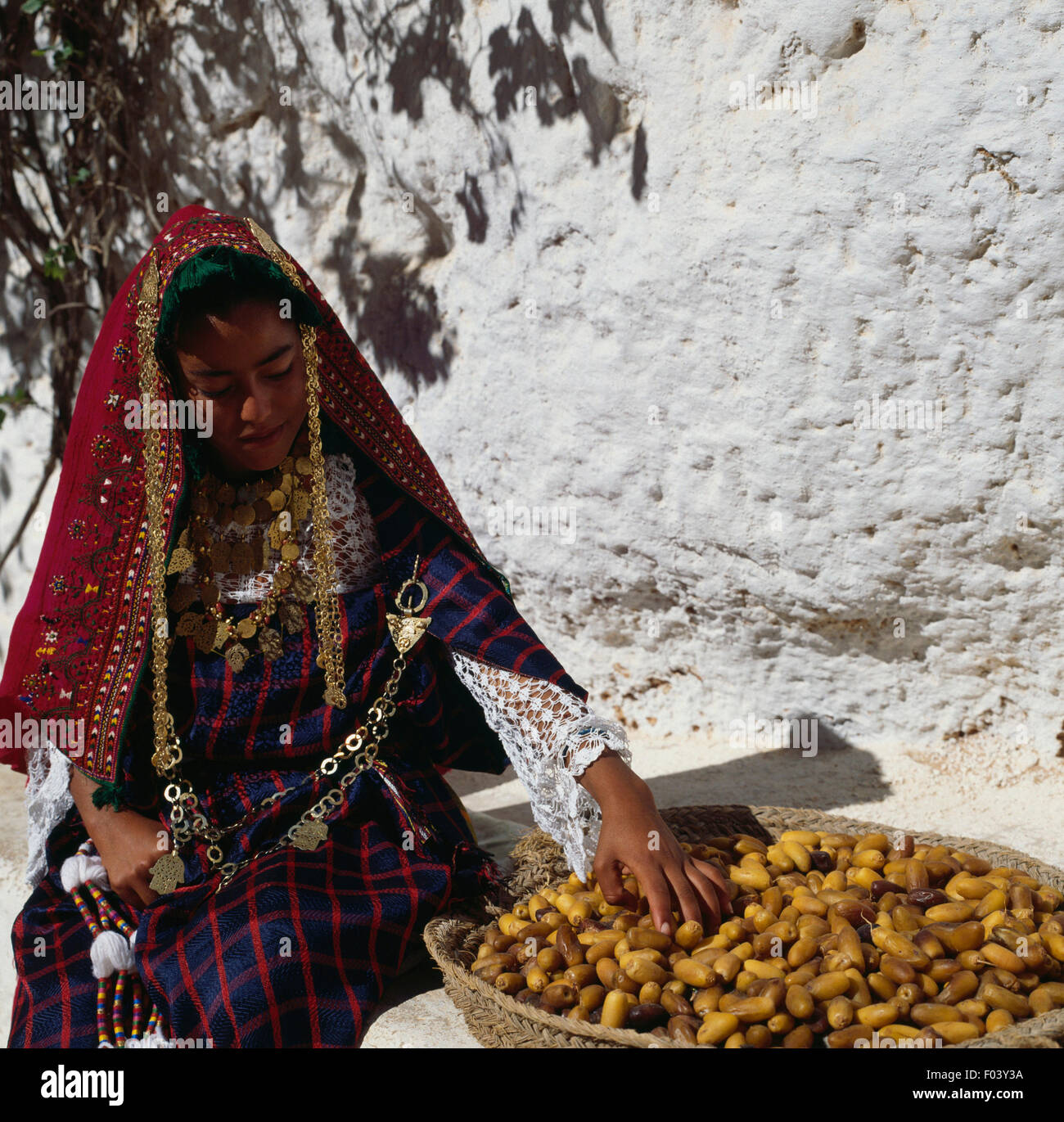 Berber girl in traditional clothes with basket of dates, Matmata, Tunisia. Stock Photo
