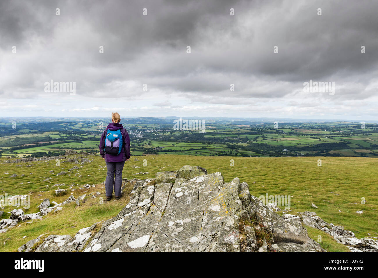 Hill Walker Enjoying the View West from the Summit of Cox Tor as Cloud Builds Above, Dartmoor, Devon UK Stock Photo