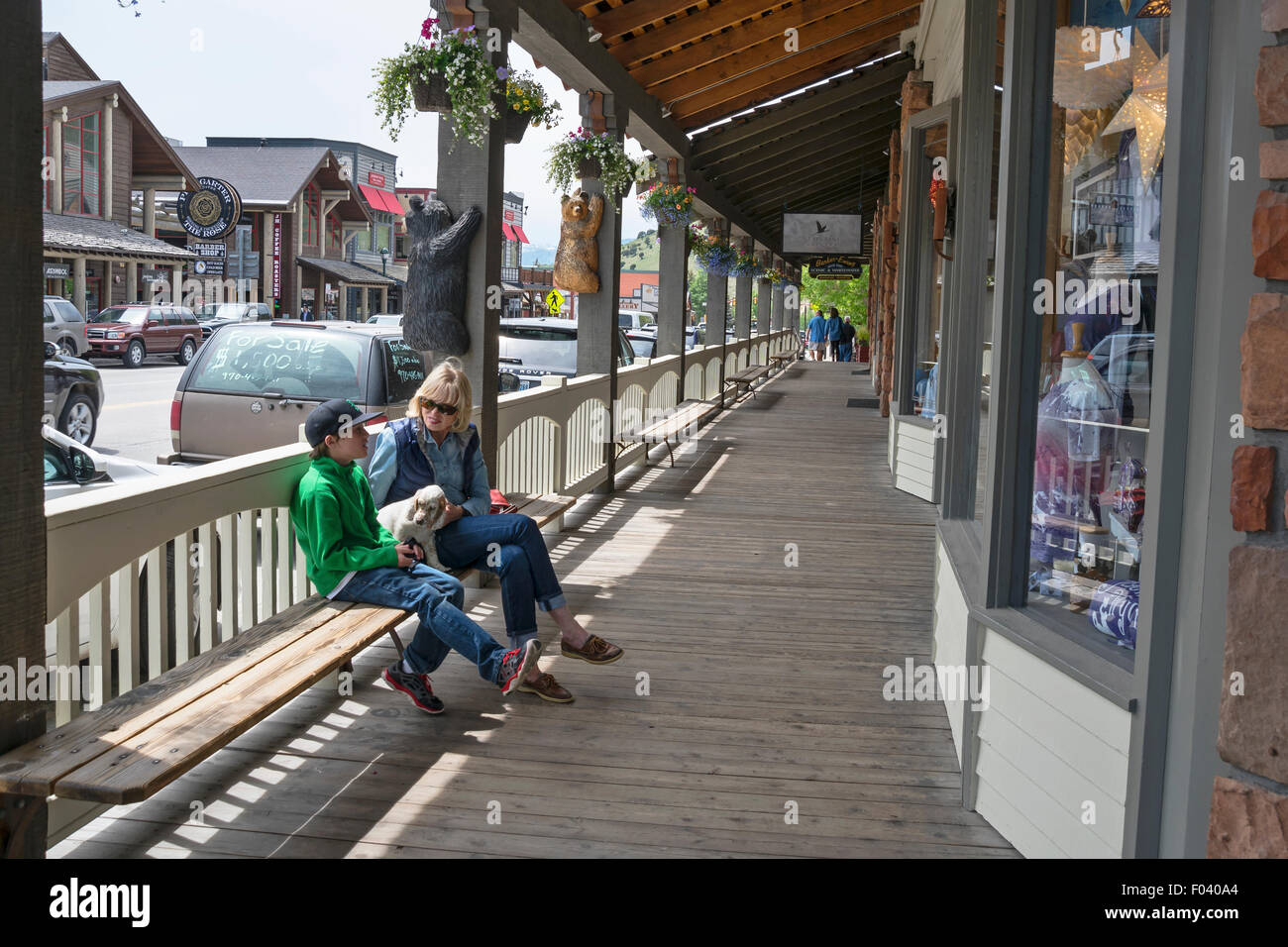 A woman and her son sitting on the bench with small white dog, Jackson