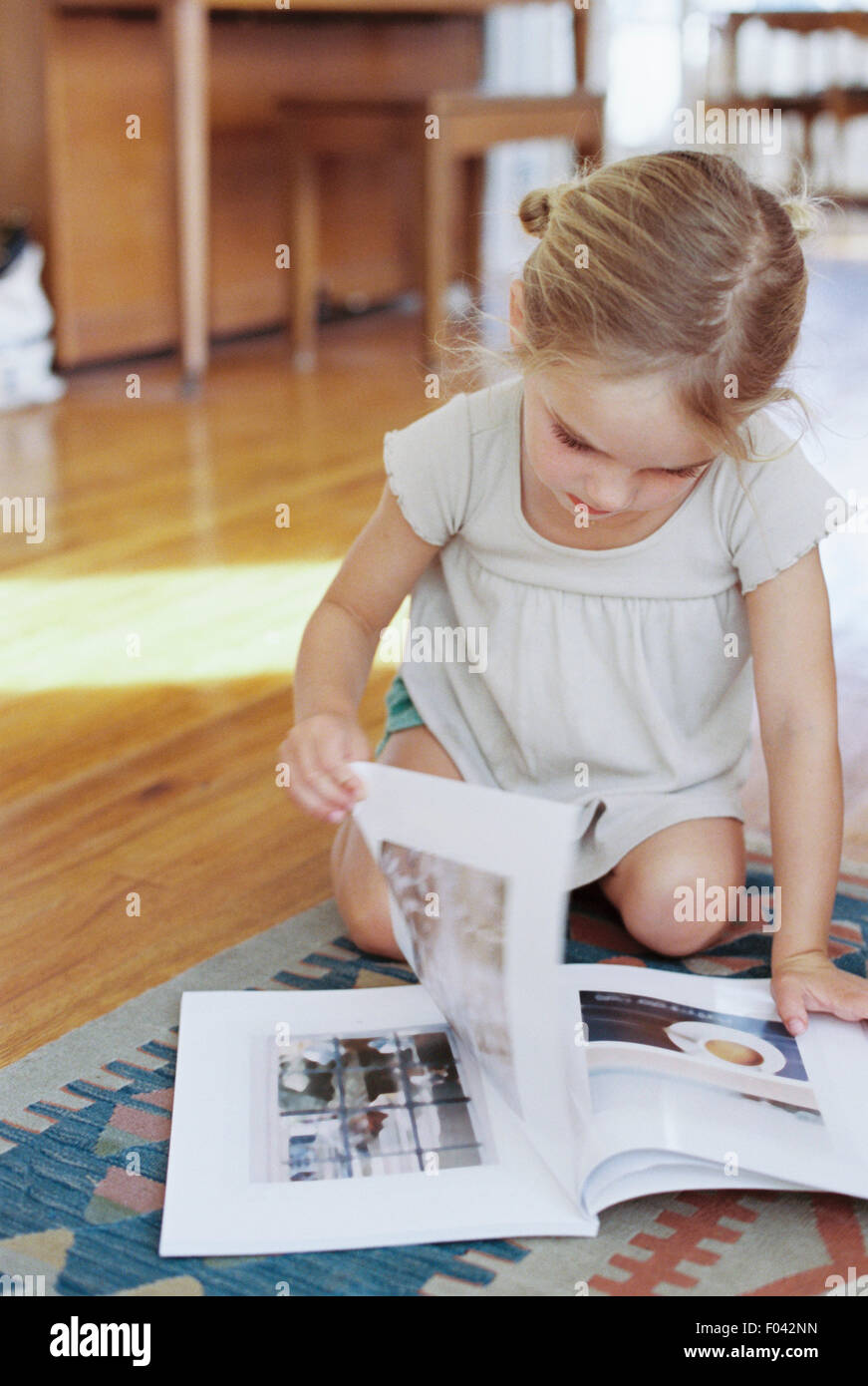 Young girl sitting on the floor, reading a lifestyle magazine. Stock Photo