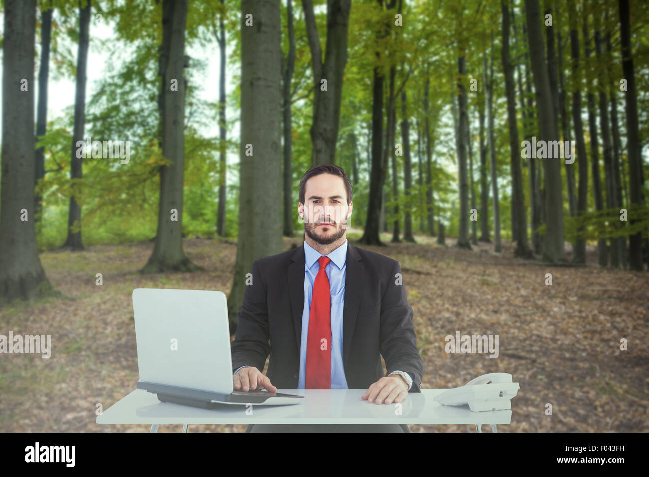 Composite image of unsmiling businessman sitting at desk Stock Photo