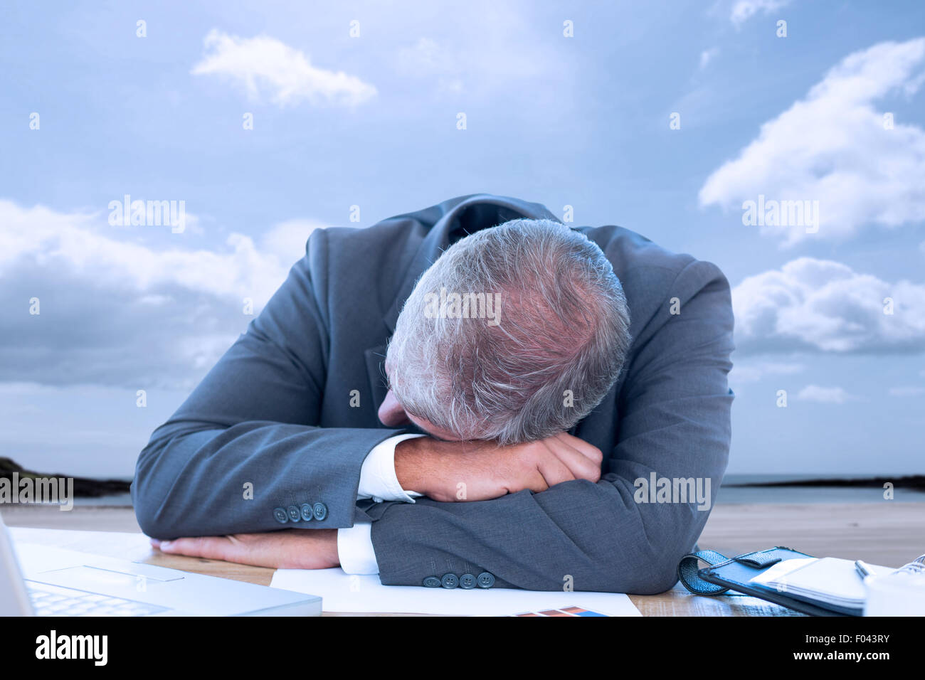 Composite image of tired businessman resting on desk Stock Photo