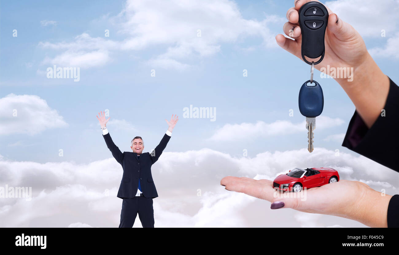 Composite image of woman holding key and small car Stock Photo