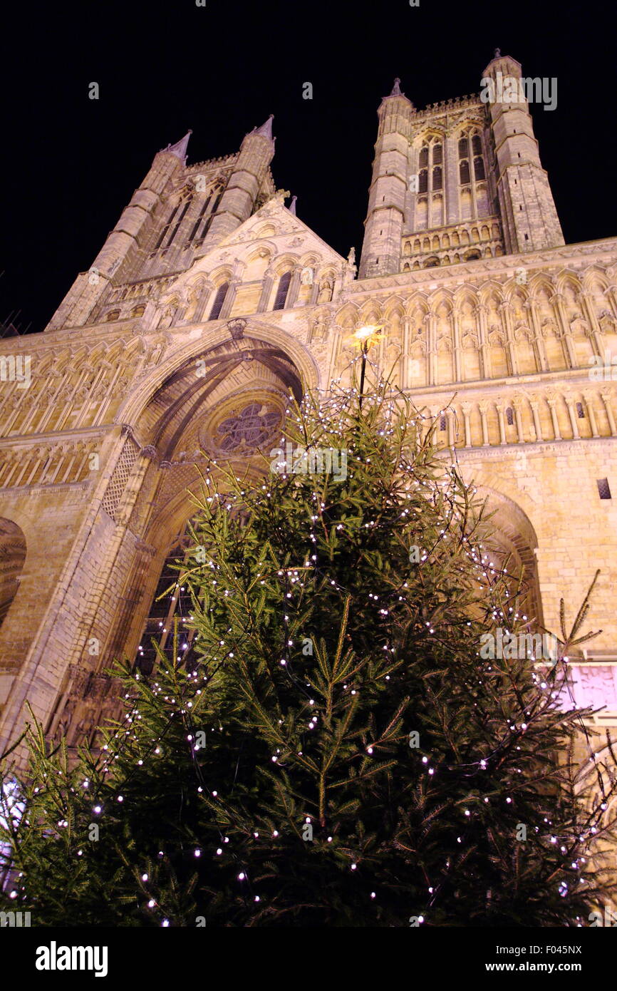A Christmas tree outside the main entrance of an illuminated Lincoln Cathedral during the City's Christmas market, England UK Stock Photo