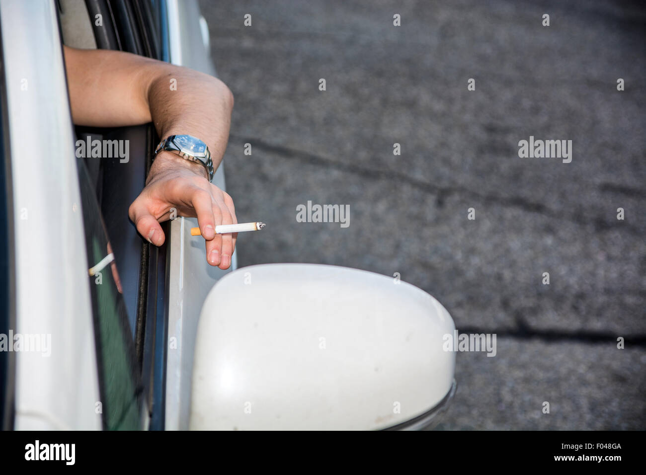 Handsome Young Man smoking cigarette while Driving a Car Stock Photo