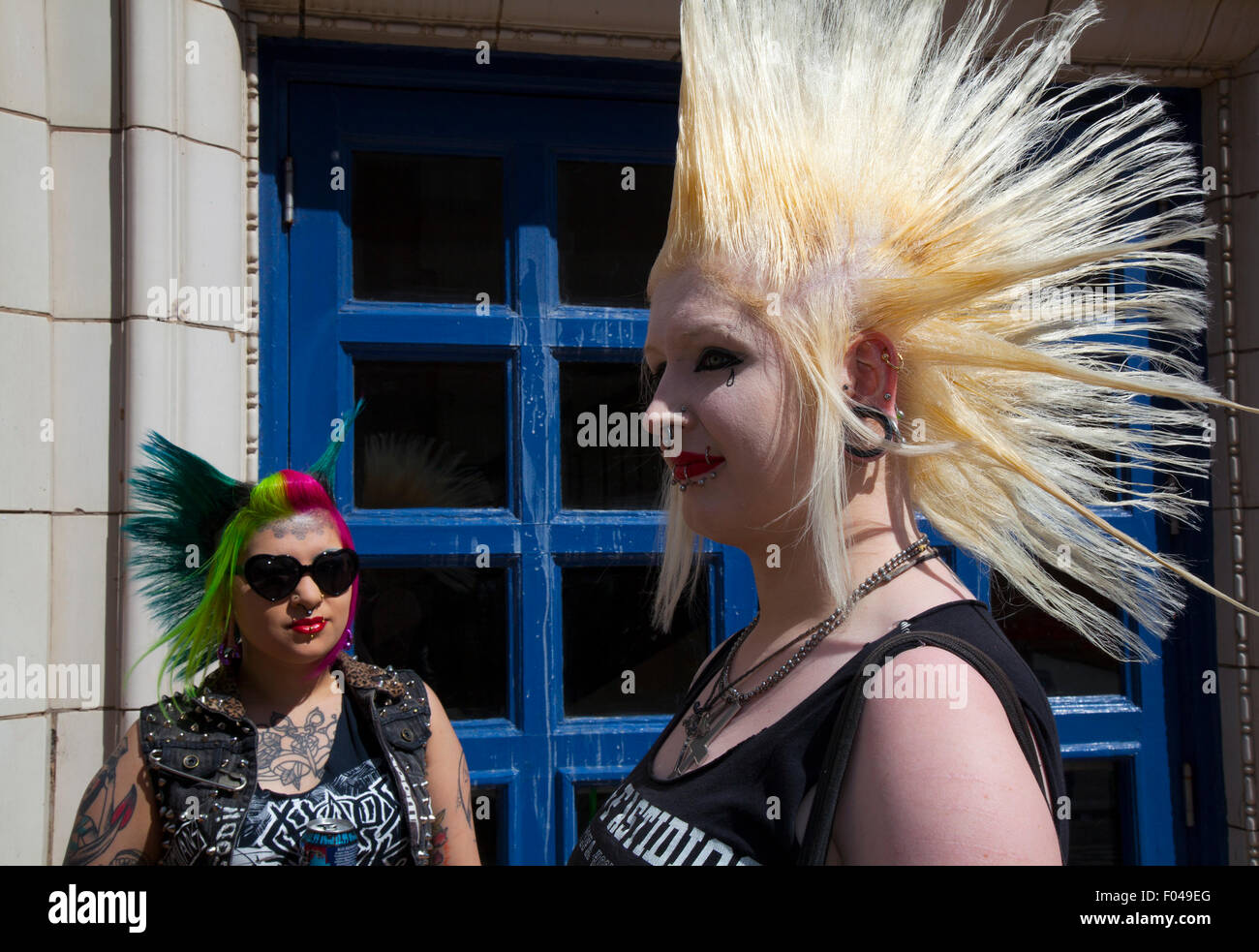 Punks with mohican dyed liberty mohican hairstyle at Blackpool, Lancashire, UK. 7th Aug, 2015. Punk Rebellion couple ,festival at The Winter Gardens. A clash cultures at the famous seaside town of Blackpool as punks, with liberty spiked hairstyles & studs, studded,  nose ring, fashionable, female, hair, skin. Women attending the annual Rebellion festival at the Winter Gardens come shoulder to shoulder with traditional holidaymakers.  Credit: MediaWorldImages/Alamy Live News Stock Photo