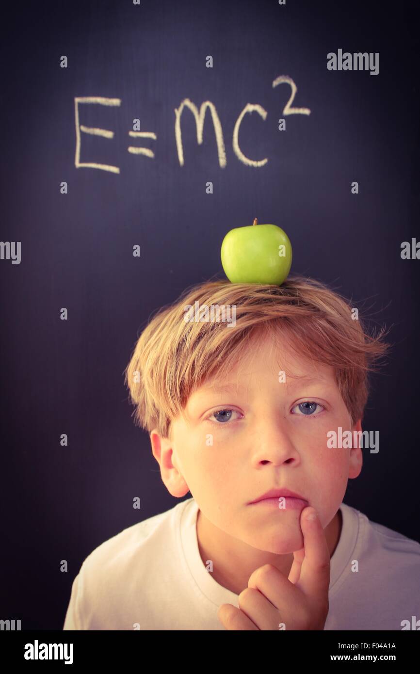 Young boy with an apple balanced on his head contemplating the theory of relativity Stock Photo