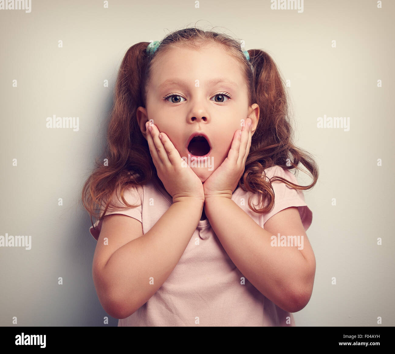 Fun surprising kid girl with opened mouth looking. Toned closeup portrait Stock Photo