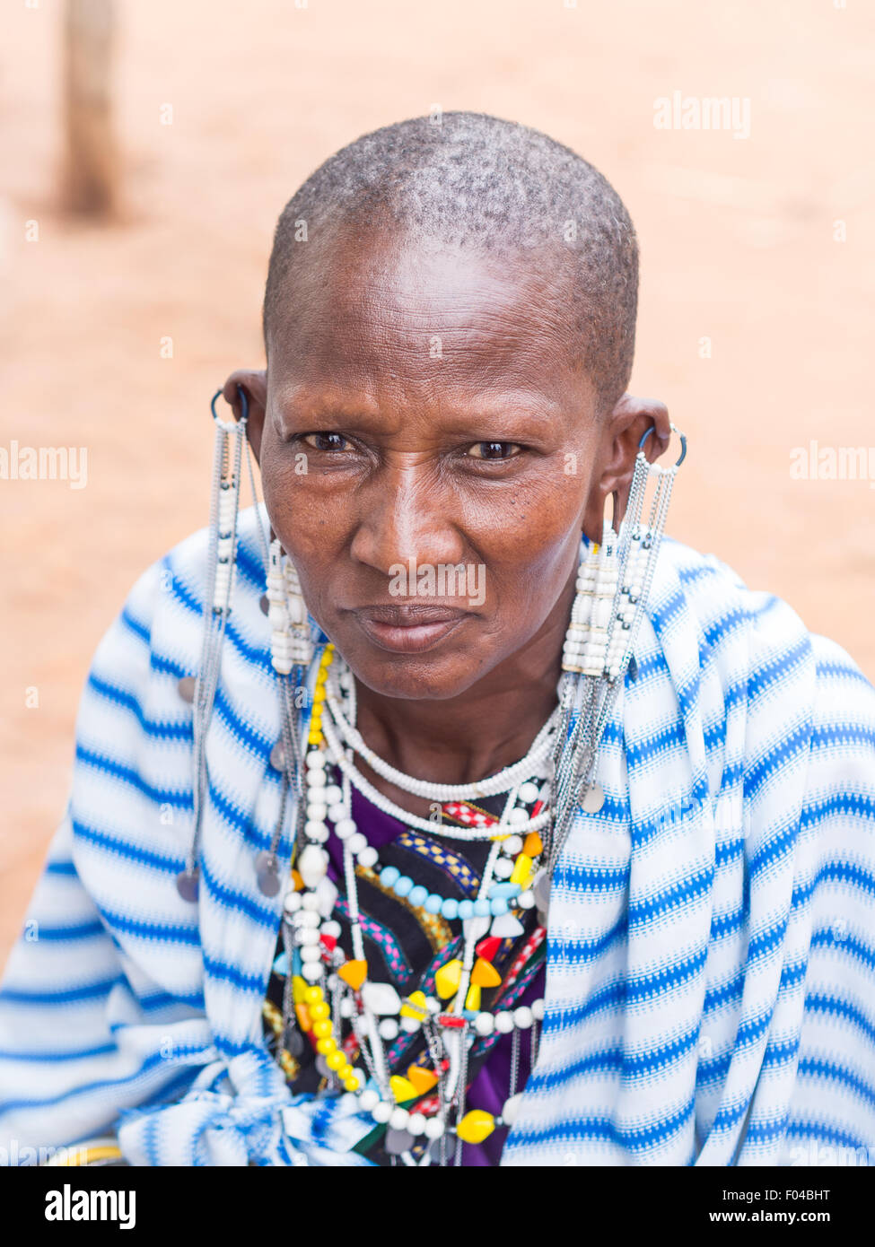 Maasai woman wearing earrings in stretched earlobes and traditional necklaces on a local market. Stock Photo