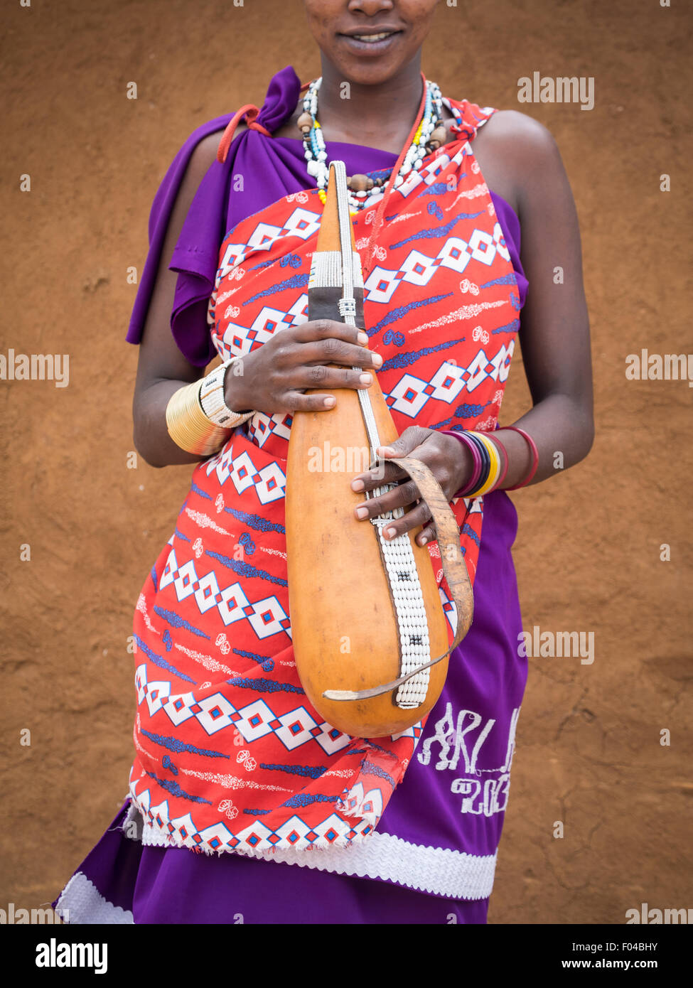 Traditional Maasai calabash used for holding milk held by a young traditionally dresses woman. Stock Photo
