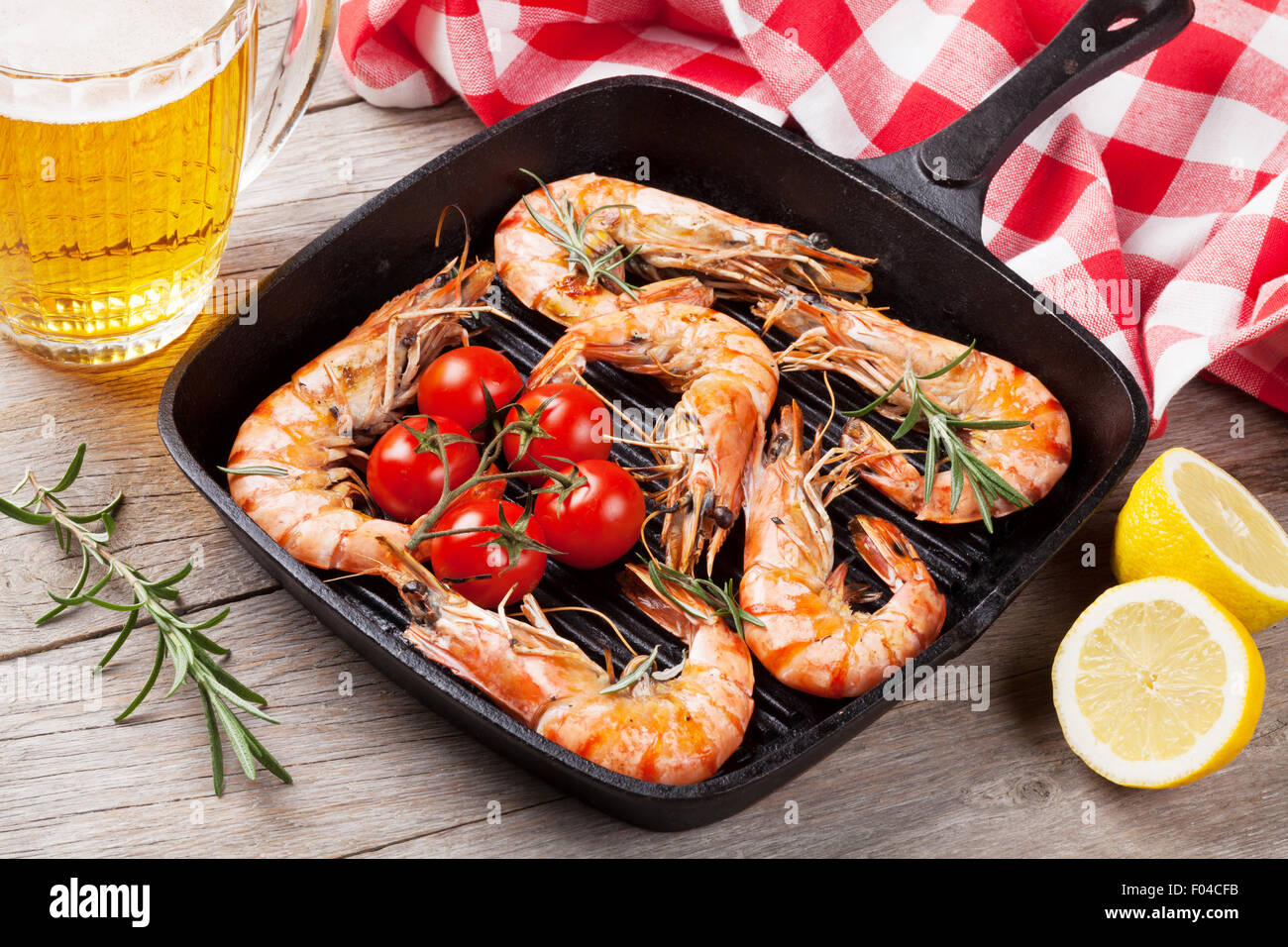 Grilled shrimps on frying pan and beer on wooden table Stock Photo