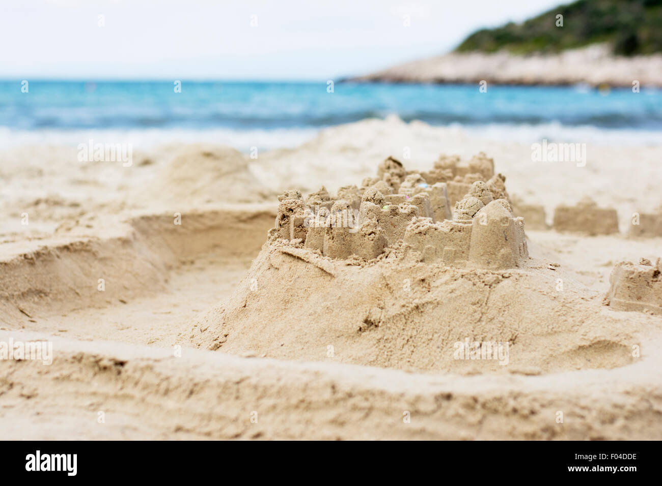 Children's sand castle on the beach with turquoise sea in background Stock Photo