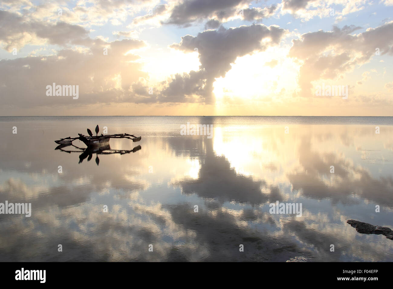 A dhow, traditional vessel used in the Indian Ocean and Red Sea region, anchored on a very calm sea at sunrise Stock Photo