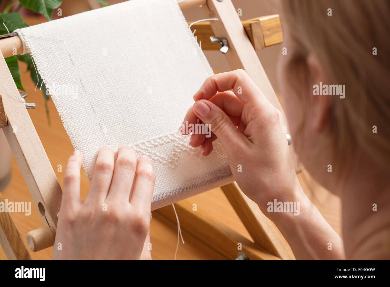 Woman hands doing cross-stitch. A close up of embroidery. Stock Photo