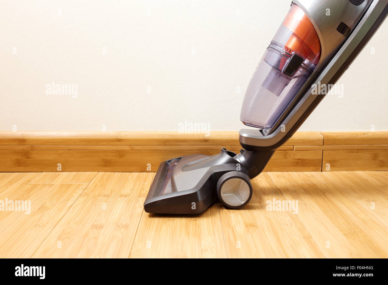 Cordless vertical vacuum cleaner cleaning parquet floor. Stock Photo