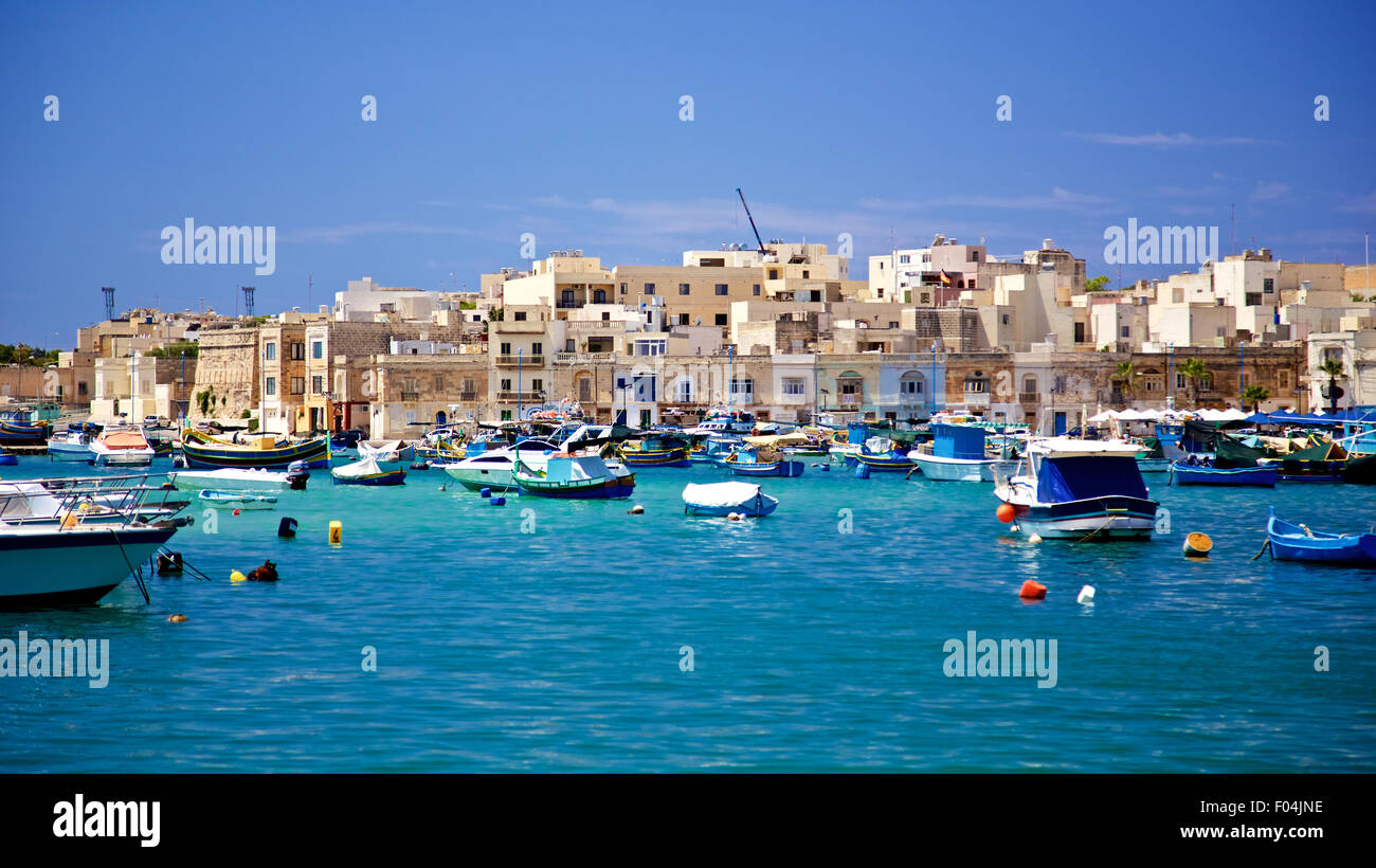 Colorful boats and moroccan style buildings in Marsaxlokk Fishing Village, Malta Stock Photo
