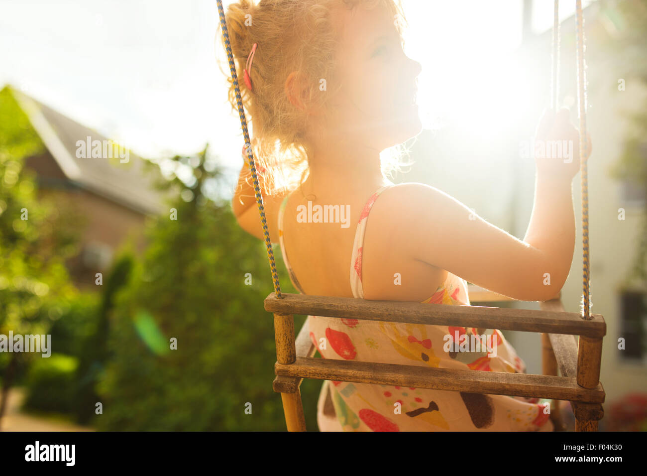 Happy girl having fun on a swing on summer day, lifestyle background