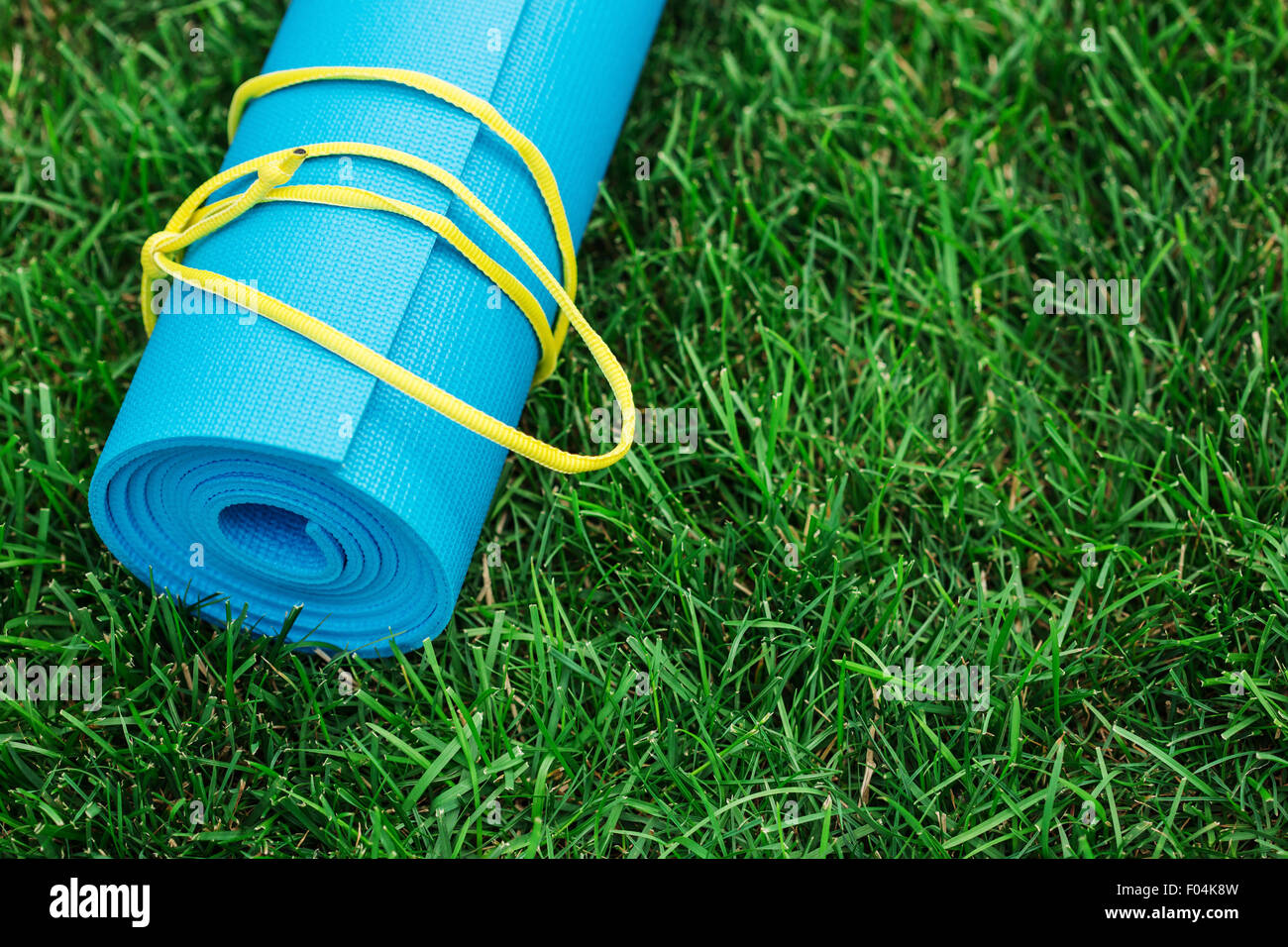 Blue yoga mat on green grass, close up photo, fitness concept Stock Photo