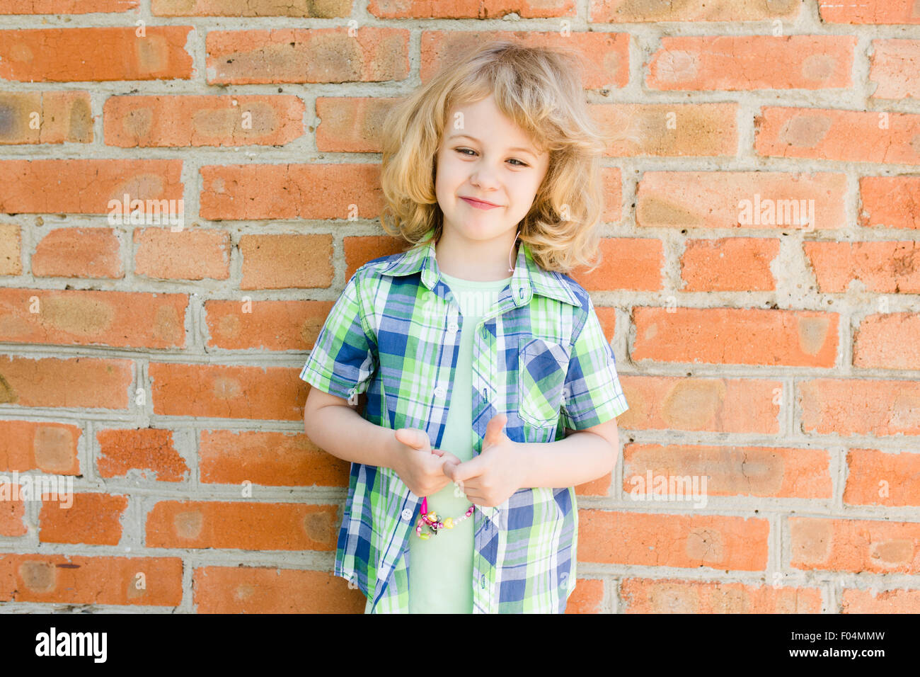 Portrait of emotional little girl in summer dress outdoor, brick wall behind Stock Photo