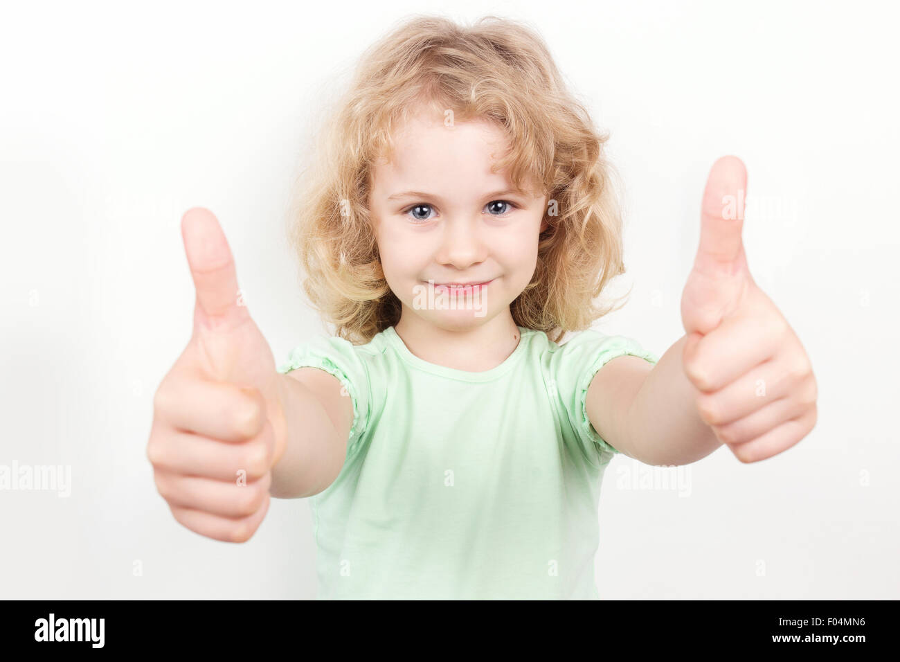 Little girl with thumbs up on white background Stock Photo