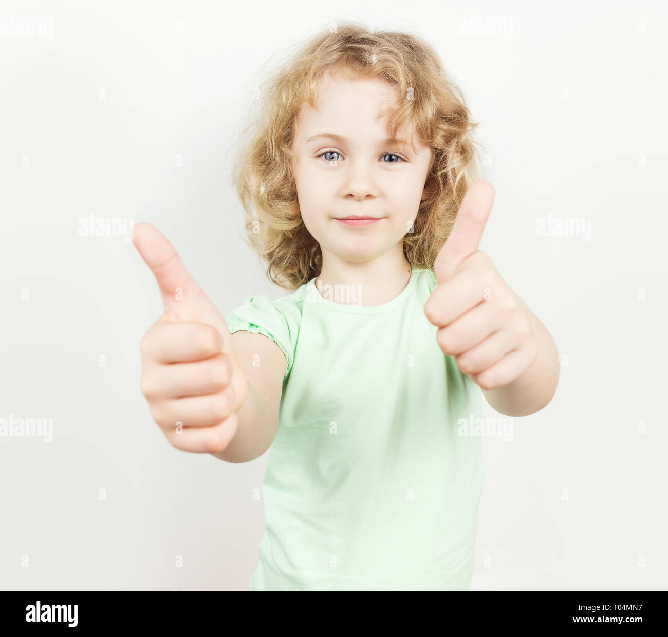 Little girl with thumbs up on white background Stock Photo - Alamy