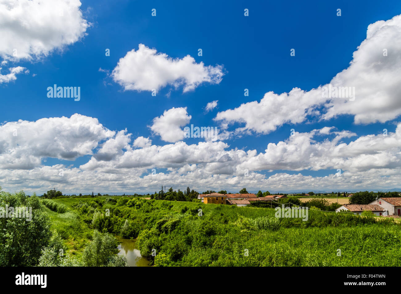river in the countryside in the north of Italy under a cloudy blue sky ...