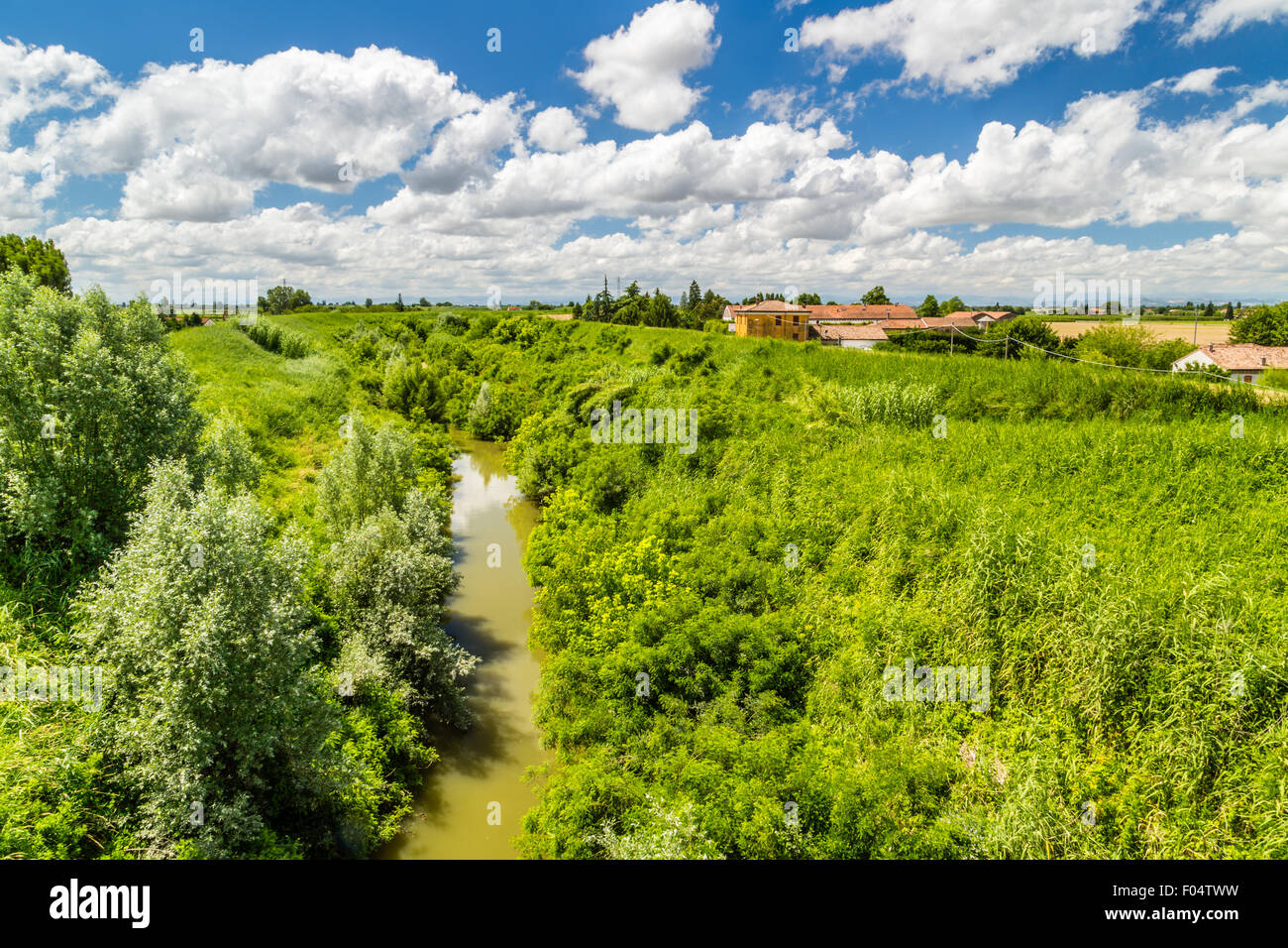 river in the countryside in the north of Italy under a cloudy blue sky ...