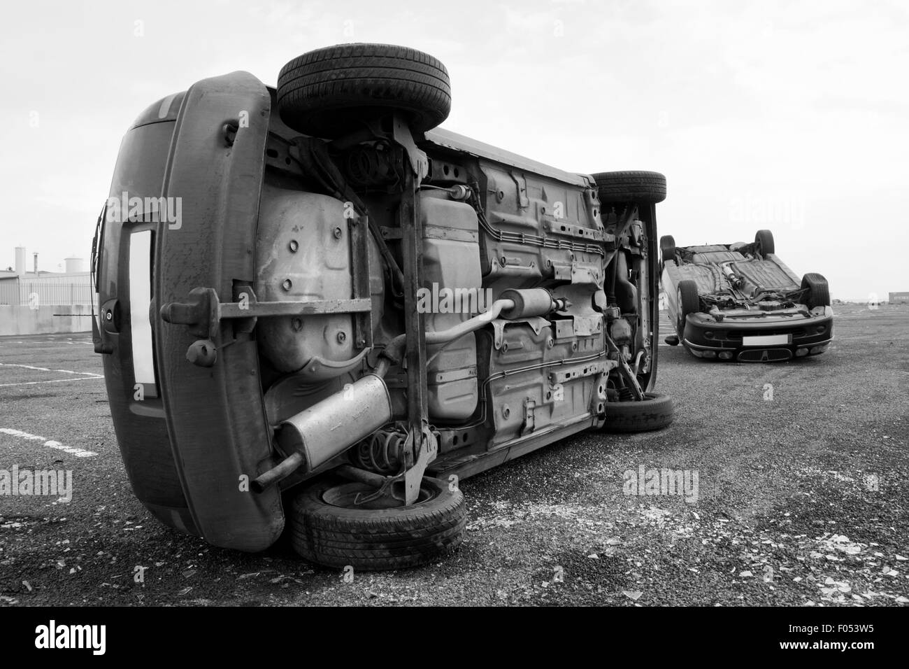 two cars turned upside-down after road collision. Monochromatic Stock Photo