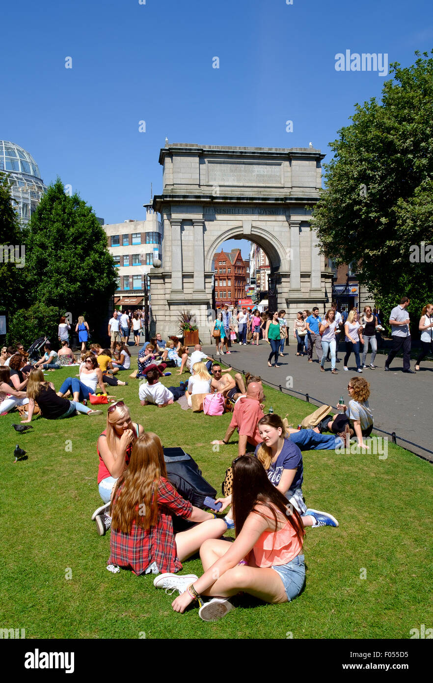 st stephens green dublin people relaxing summer lunch break sitting grass arch archway entrance Stock Photo