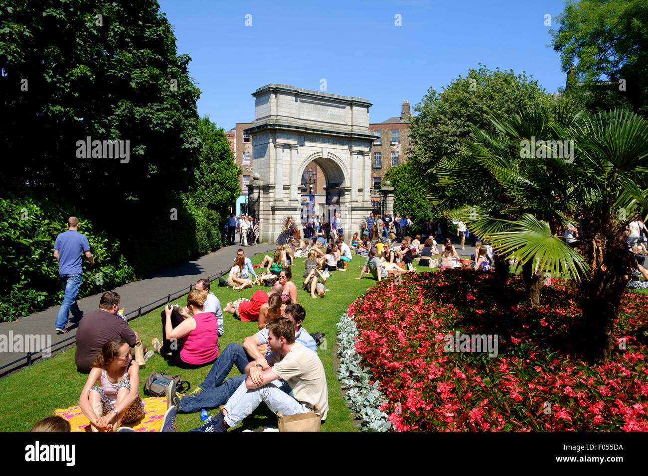 st stephens green dublin people relaxing summer lunch break sitting grass arch archway entrance Stock Photo