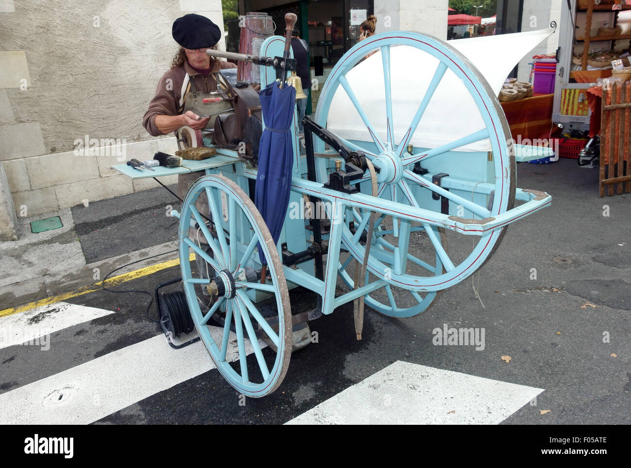Traditional knife grinder outside market in small town of Nay near Pau ...