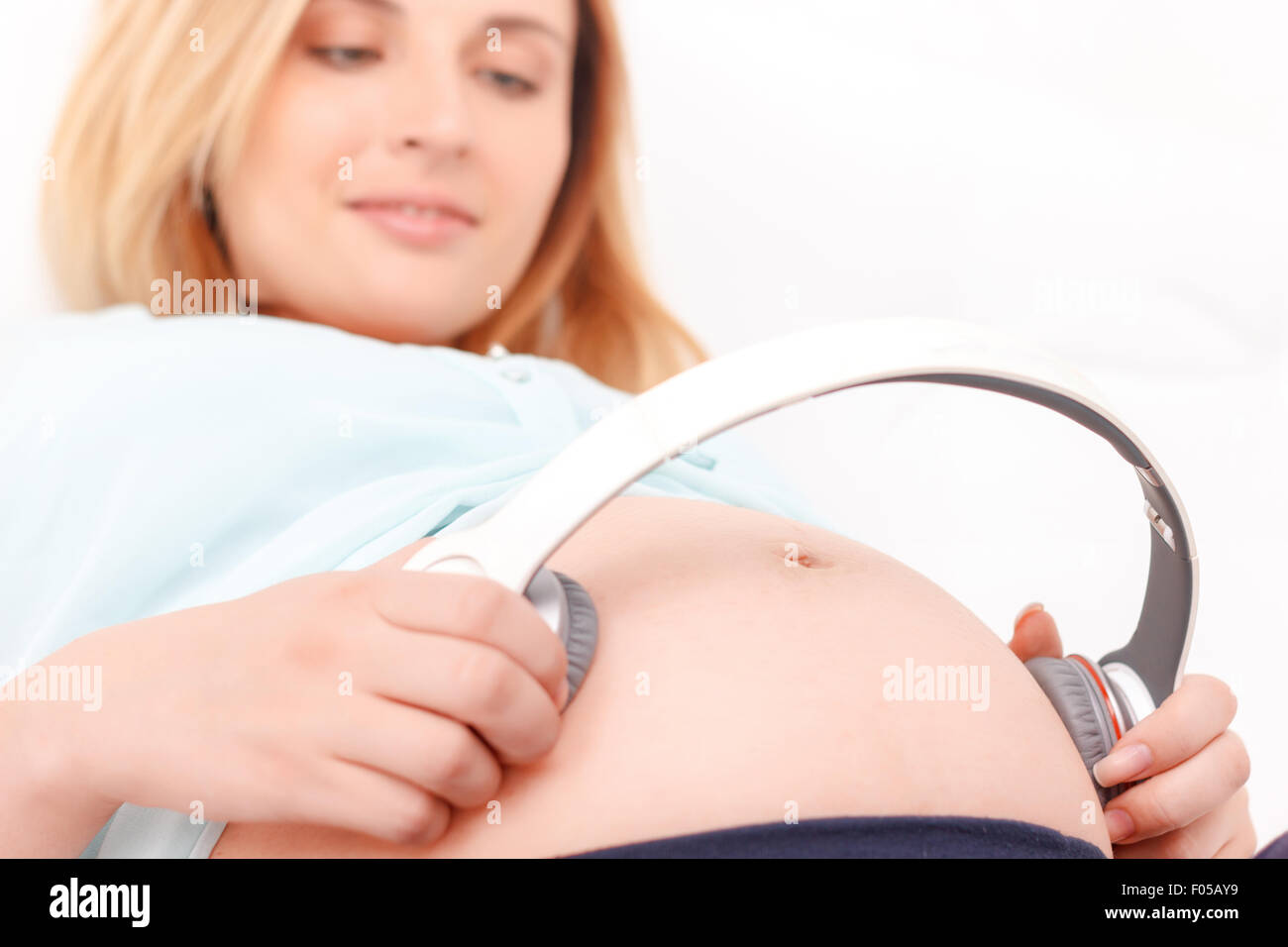 Pregnant woman with headphones on tummy Stock Photo