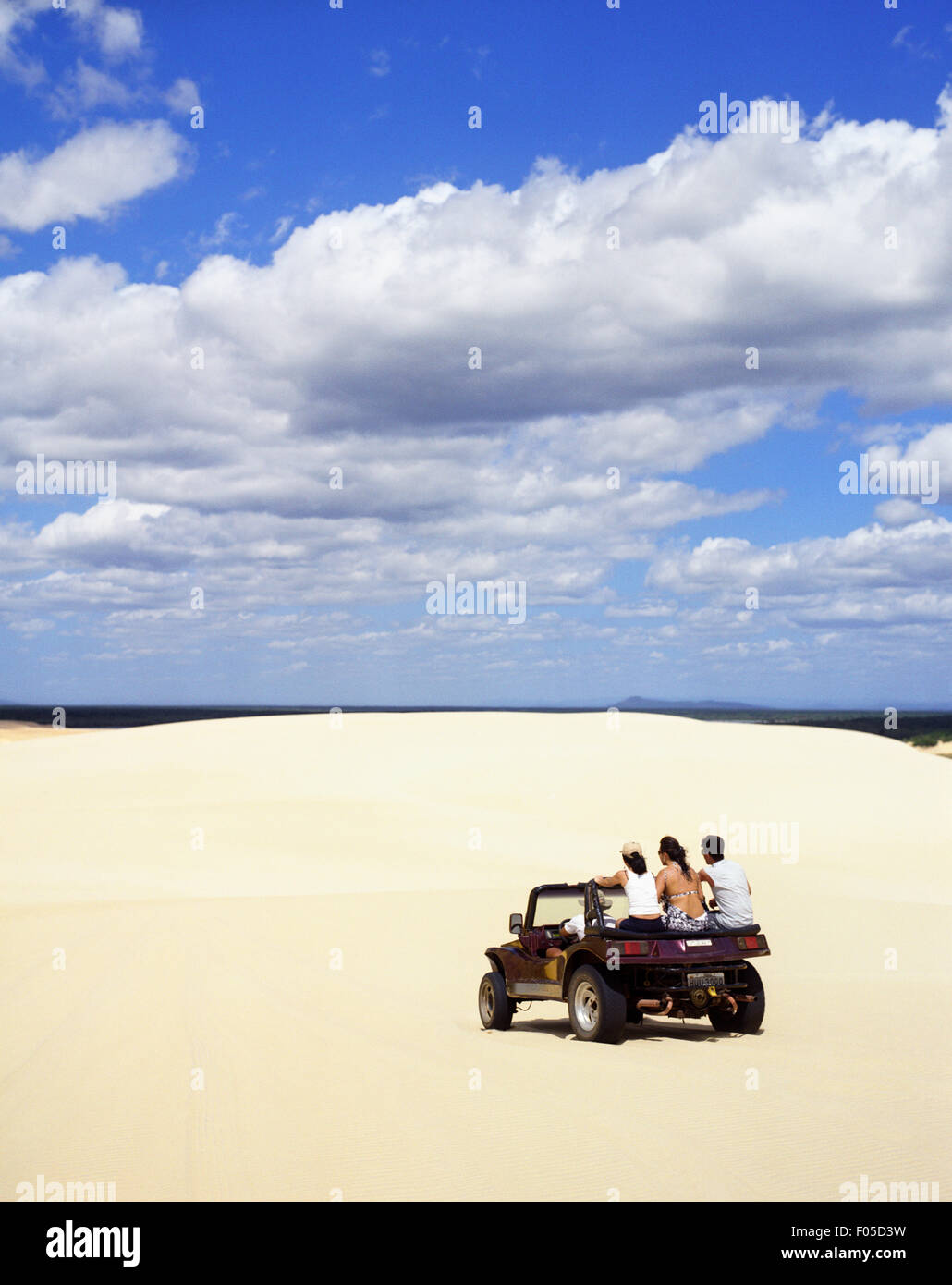 A group of friends drive a dune buggy across the sands at Dunas Tatajuba, just outside of Jericoacara, Brazil Stock Photo