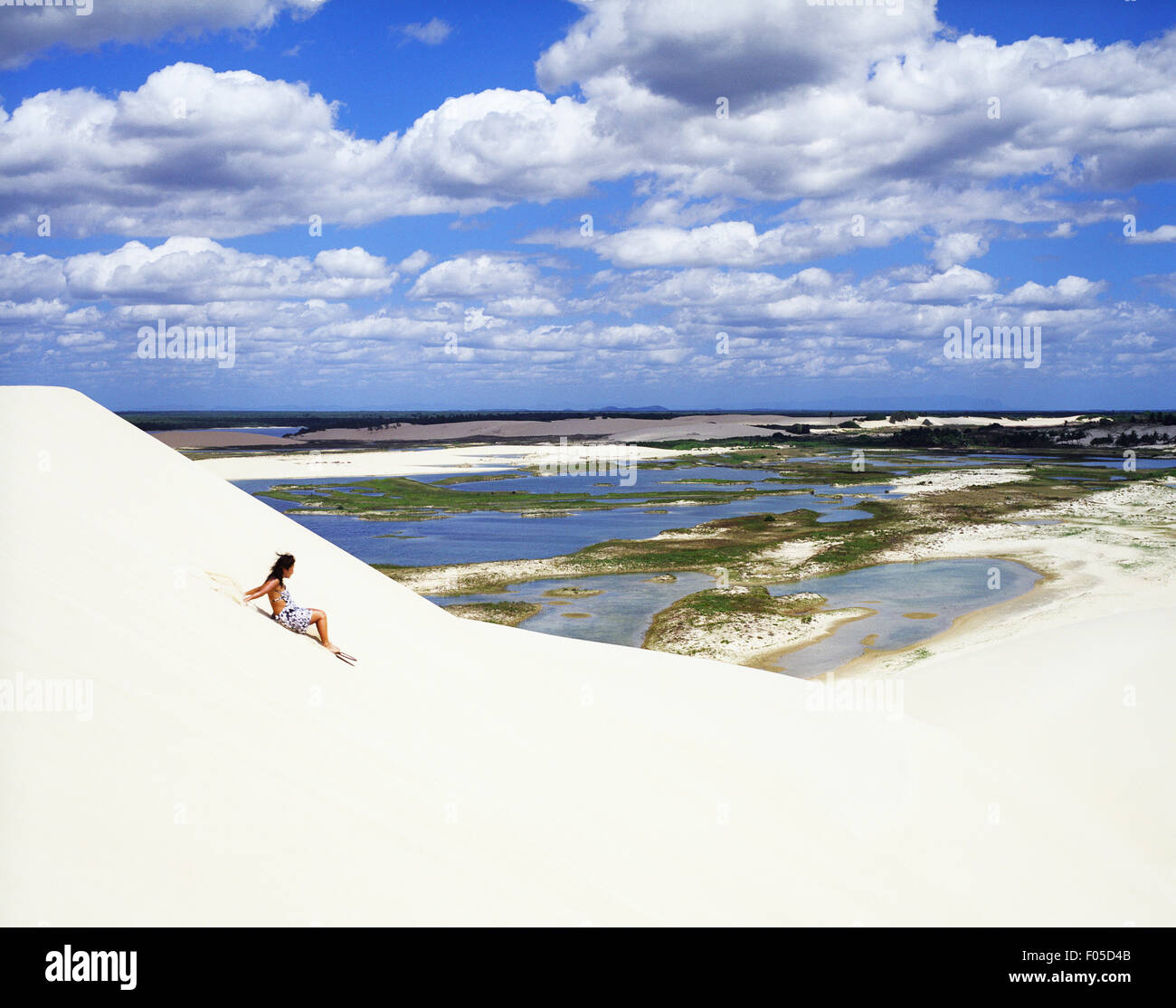 A woman rides a board down a sand dune at Dunas Tatajuba, just outside of Jericoacoara, Brazil. Stock Photo