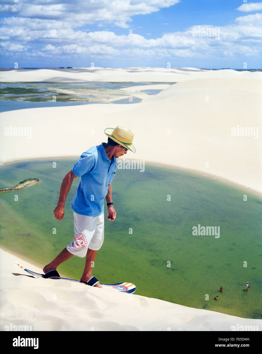 A Brazilian man climbs a dune to take another run sand boarding down a dune at Dunas Tatajuba, Jericoacoara, Brazil Stock Photo