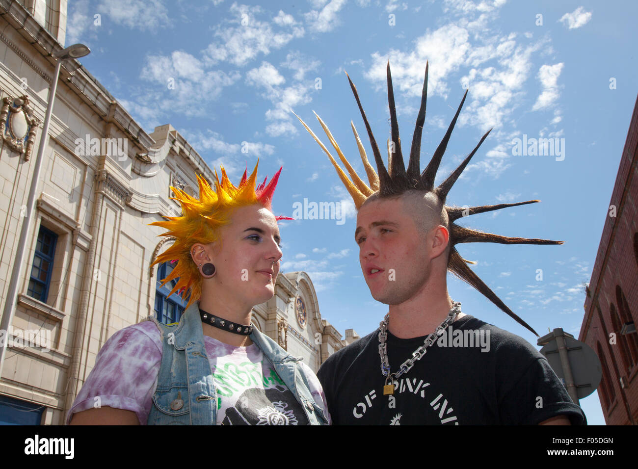Two Punks with dyed hair, Mohawk Liberty spikes mohican hairstyle at Blackpool, Lancashire, UK. Aug, 2015. Punk Rebellion festival at The Winter Gardens. A couple clash cultures at the famous seaside town of Blackpool as punks attending the annual Rebellion festival at the Winter Gardens come shoulder to shoulder with traditional holidaymakers.  Credit: MediaWorldImages/Alamy Live News Stock Photo