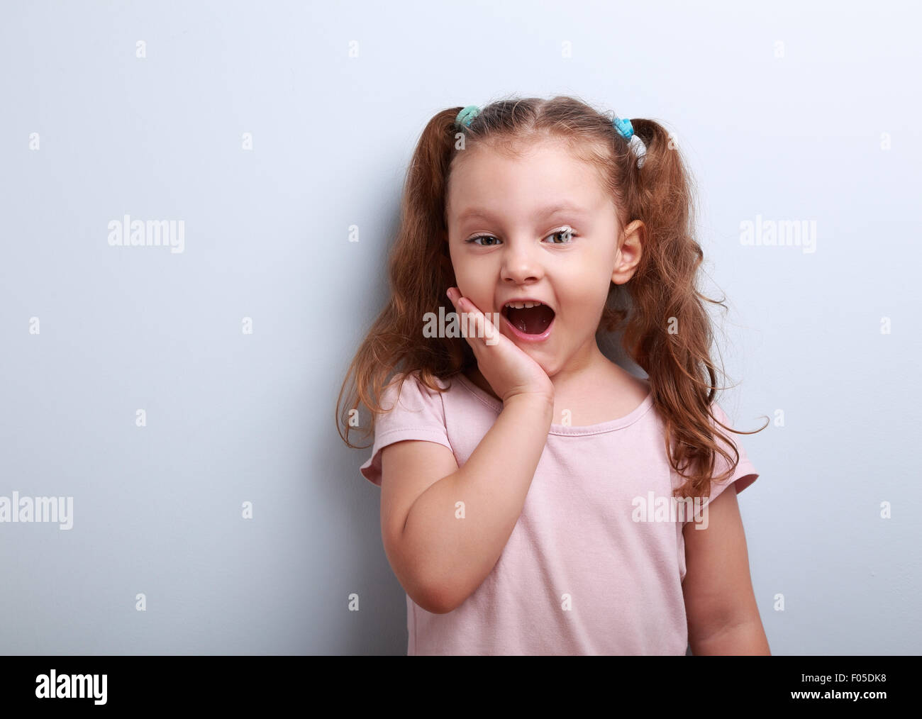 Surprising fun girl looking with open mouth on blue background Stock Photo
