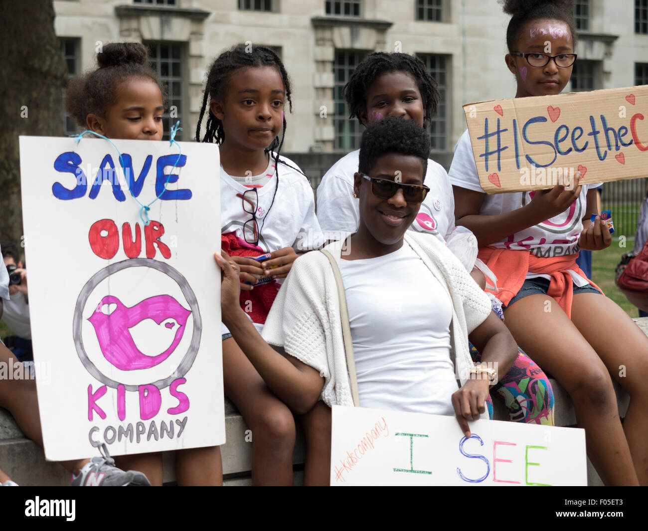 Whitehall, London, UK, 7 August 2015. Children and a young woman taking part in a protest opposite Downing Street aimed at saving Kids Company hold up home made placards. Credit:  Richard Slater/Alamy Live News Stock Photo