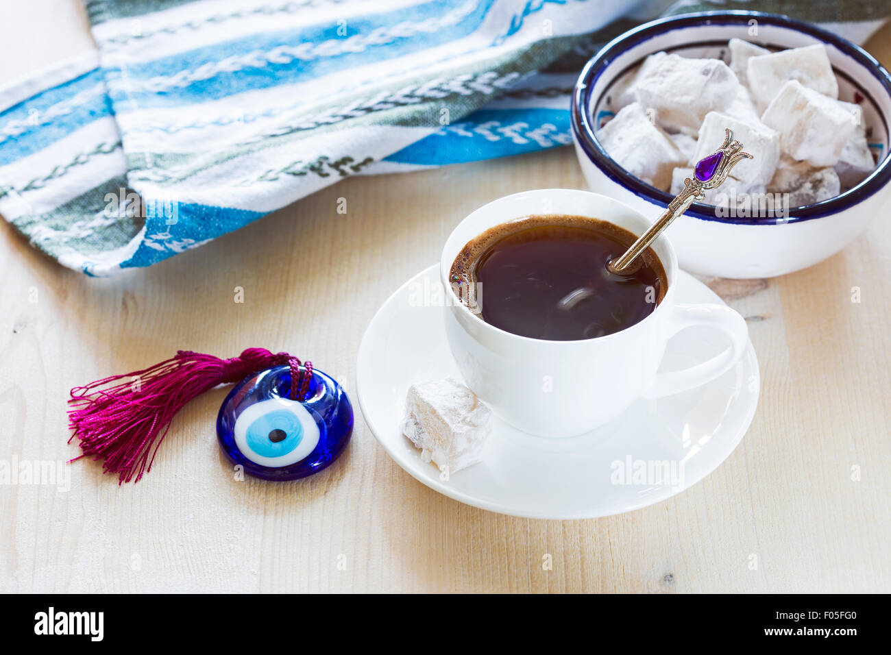 Cup of coffee with Turkish sweets and glass amulet Evil Eye on wooden background Stock Photo