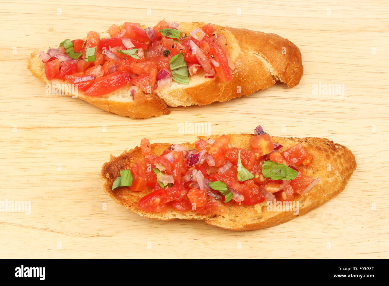 Two tomato and red onion bruschetta on a wooden board Stock Photo