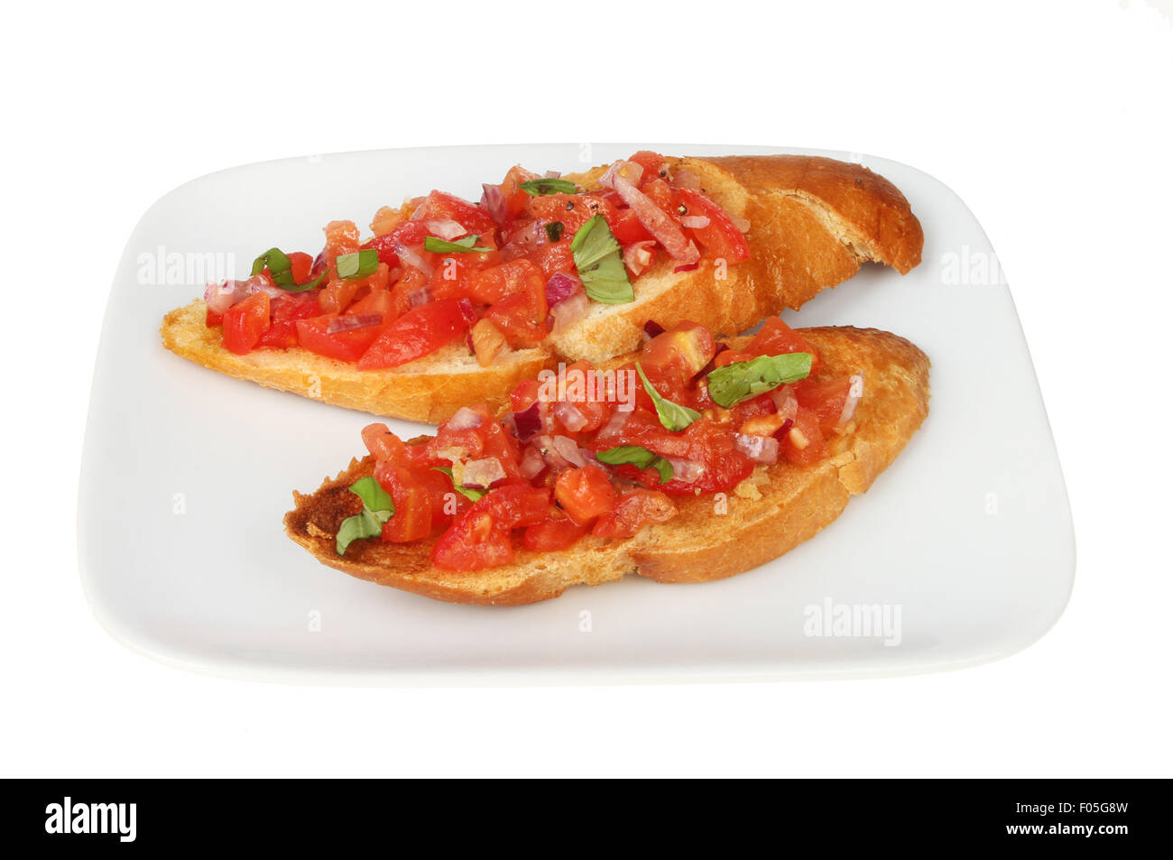 Two tomato, red onion and basil bruschetta on a plate isolated against white Stock Photo