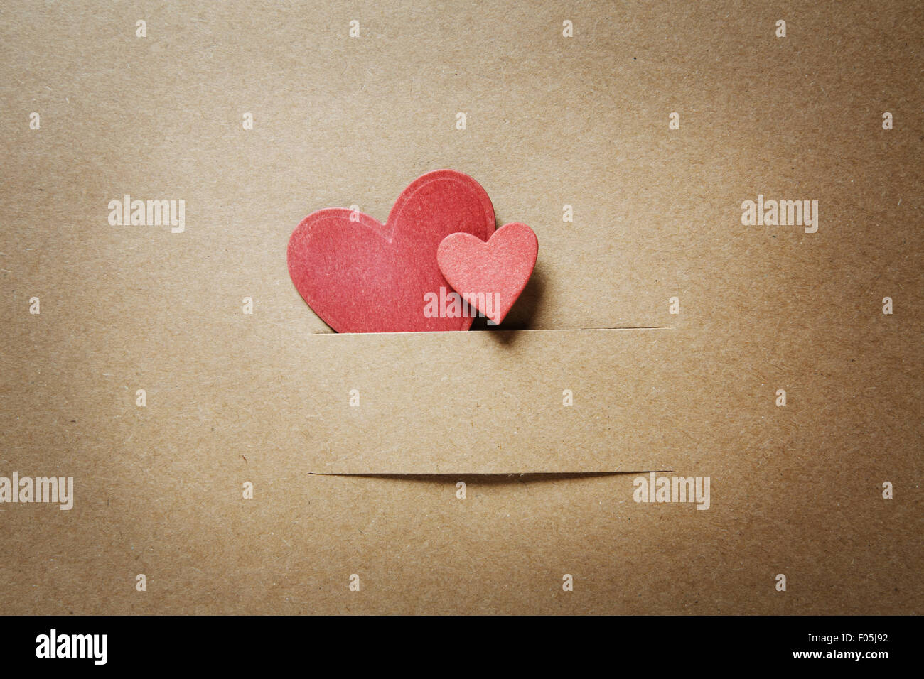 Small paper cut red hearts on earthy colored paper Stock Photo