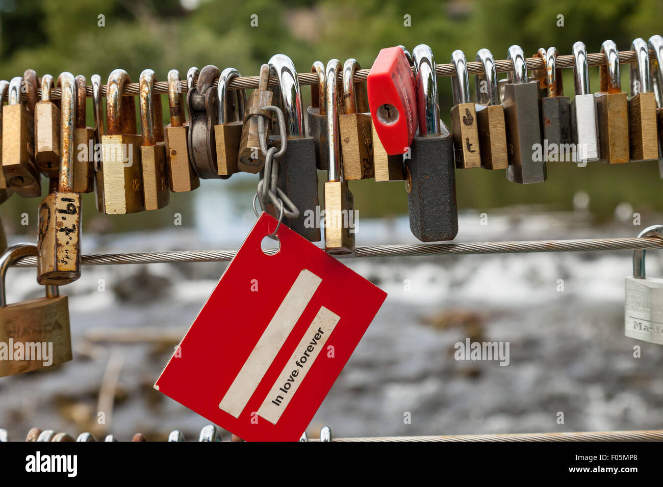 Love locks attached to the cable on weir bridge, Bakewell, Derbyshire, England, UK, Stock Photo