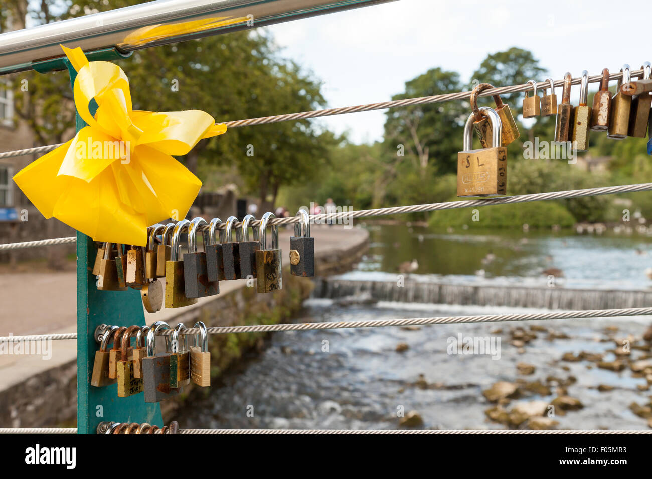 Love locks attached to the cable on weir bridge, Bakewell, Derbyshire, England, UK, Stock Photo