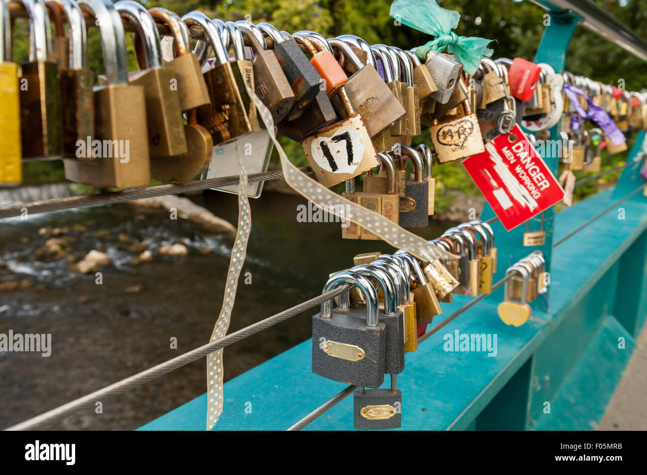 Love locks attached to the cable on weir bridge, Bakewell, Derbyshire, England, UK, Stock Photo