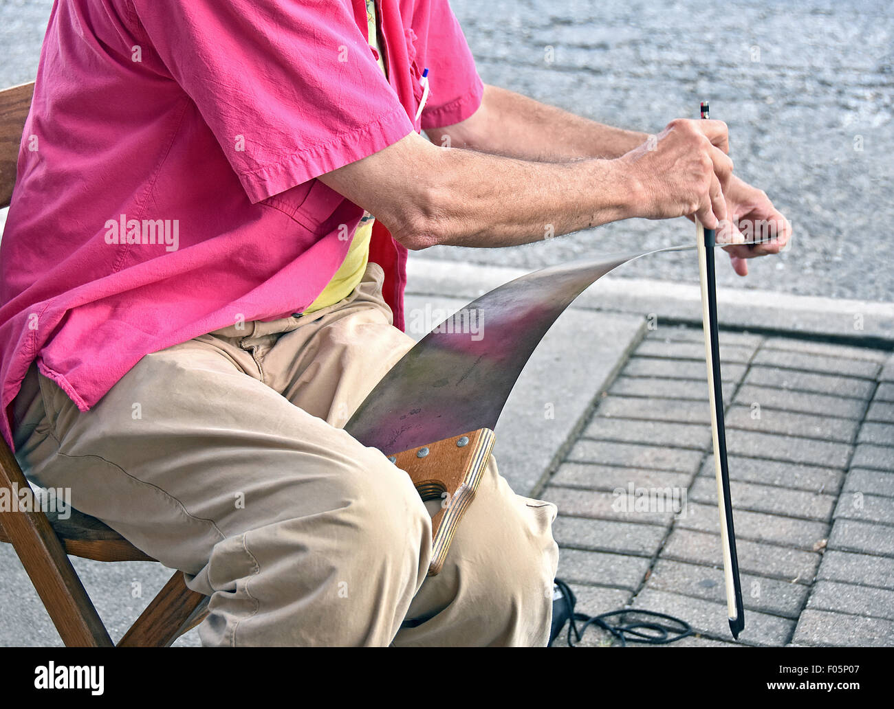 Old man playing music on a hand saw with bow. Stock Photo