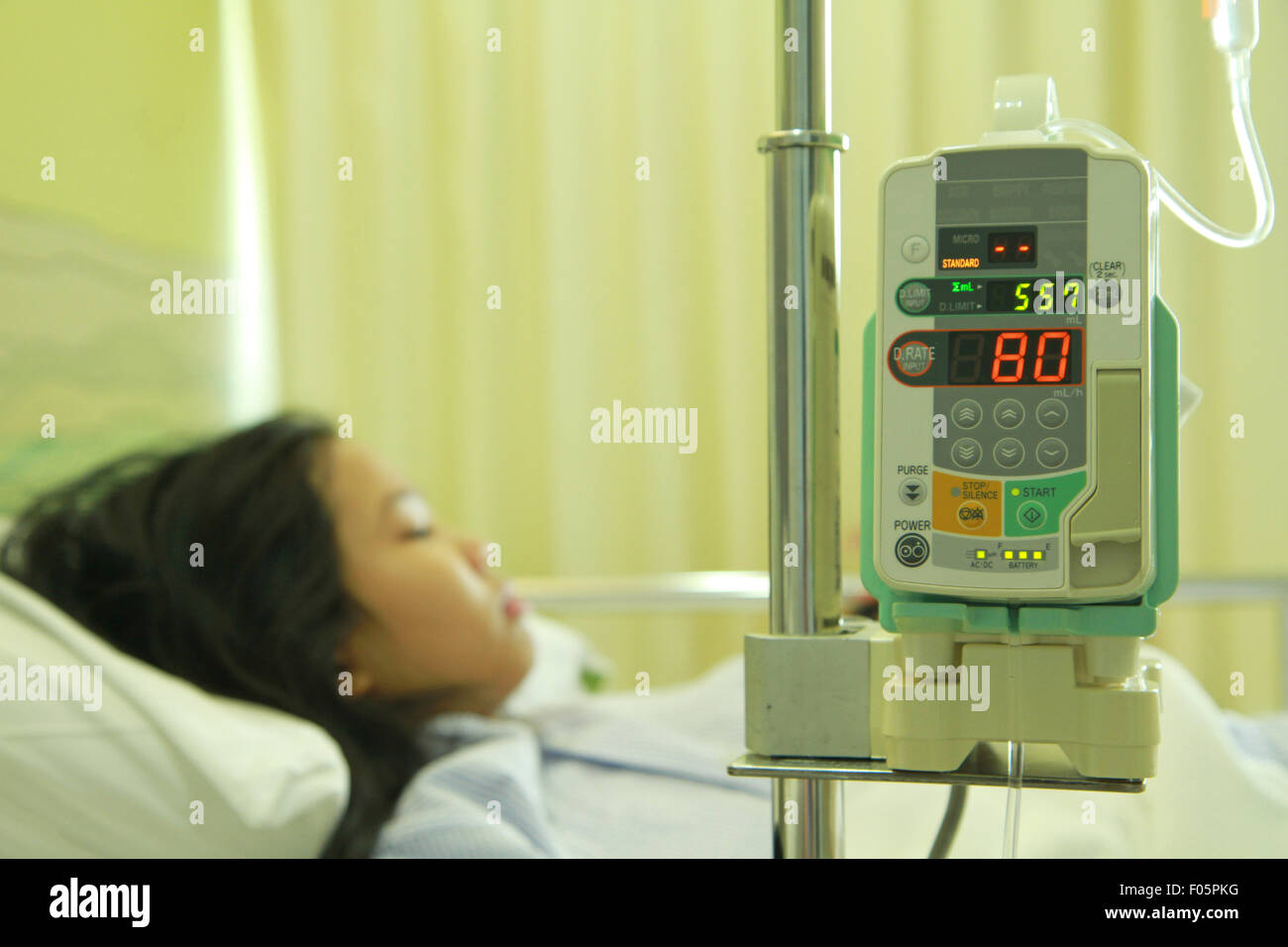 Medical infusion drip tool with patient on hospital bed in background