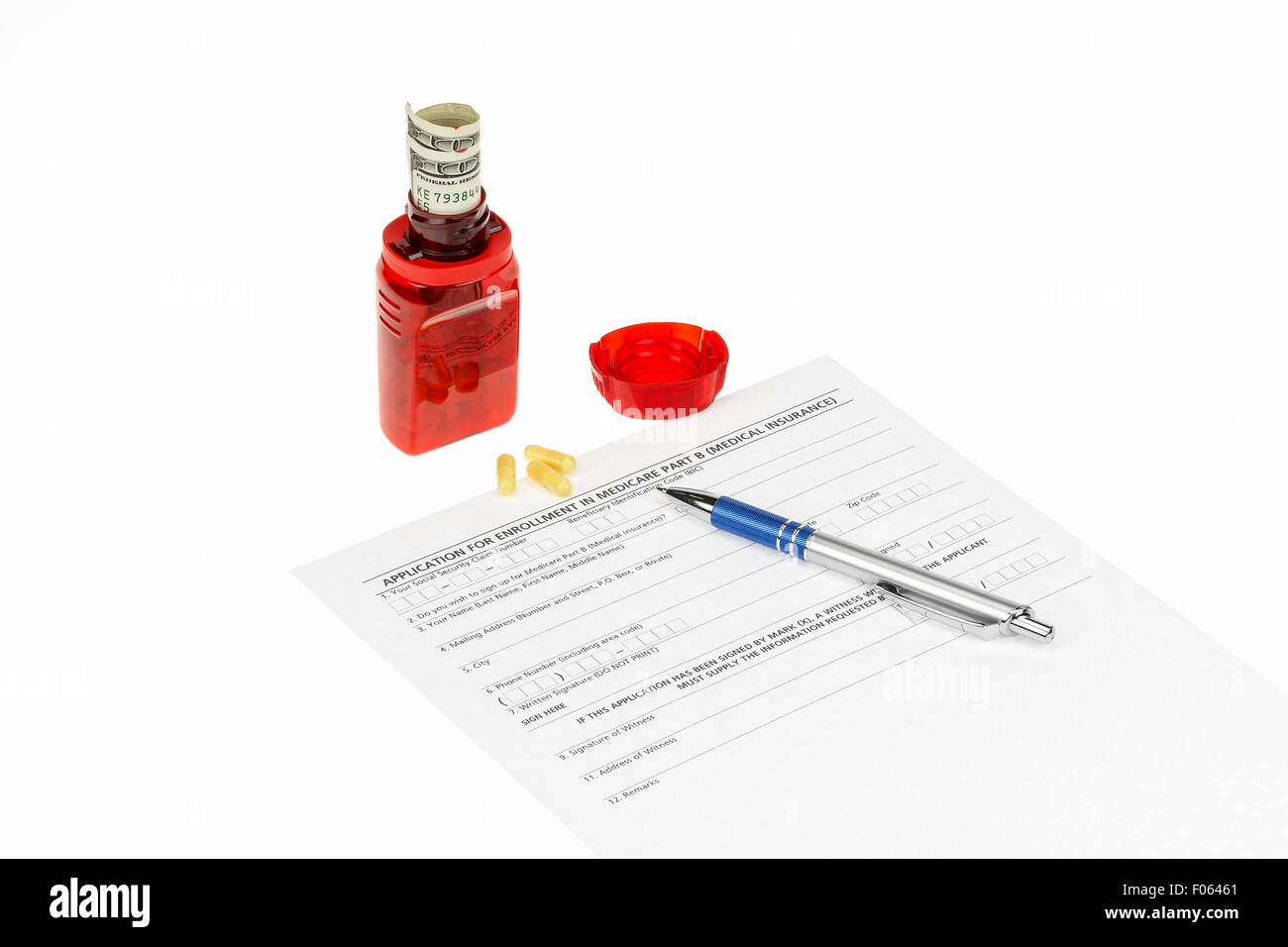 Medicare application, pen and a pill bottle with money coming out of the top on a white background. Stock Photo