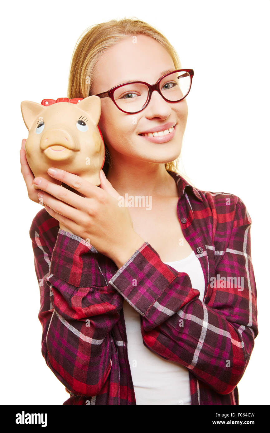 Smiling female teenager with glasses and a piggy bank in her hands Stock Photo